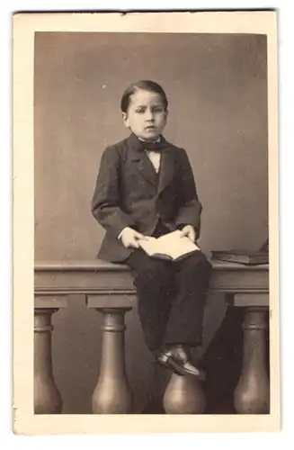 Fotografie Carl von Jagemann, Wien, junger Knabe im Anzug mit Fliege sitzt auf einem Geländer