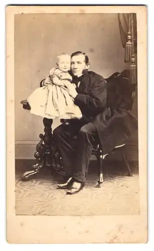 Fotografie F. König, Hamburg, junger Vater mit Backenbart und seiner Tochter auf dem Tisch