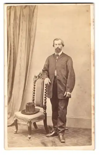 Fotografie unbekannter Fotograf und Ort, älterer Herr im Anzug mit Vollbart und hohen Hut auf dem Stuhl