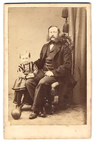 Fotografie A. F. Knoop, Eutin, älterer Herr im dunklen Anzug mit seiner Tochter im karierten Kleid, Backenbart