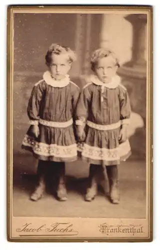 Fotografie Jacob Fuchs, Frankenthal, zwei niedliche Zwillings Mädchen posieren in gleichen Kleidern, blonde Locken