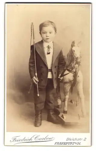 Fotografie Friedrich Carbow, Frankfurt / Main, junger Knabe im Anzug mit Peitsche nebst Schaukelpferd