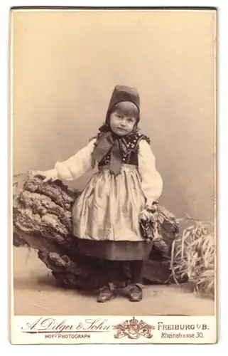 Fotografie A. Dilger & Sohn, Freiburg i. B., niedliches kleines Mädchen Annemy Eschweiler in Tracht, Studiokulisse