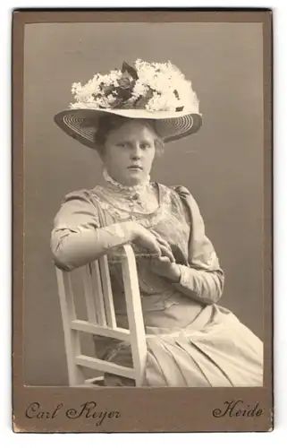 Fotografie Carl Reyer, Heide, junge Frau im schicken Kleid mit Blumen geschmücktem Hut