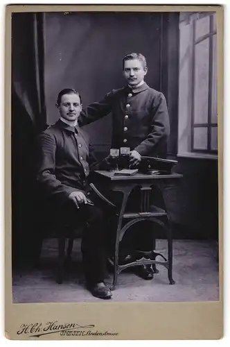 Fotografie H. Ch. Hansen, Gnesen, zwei junge Beamte mit Schwarzbier im Atelier, Wilhelm Sommer rechts