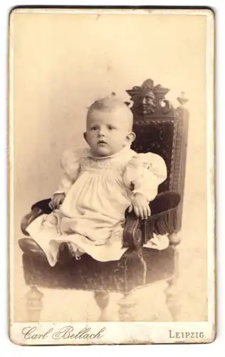 Fotografie Carl Bellach, Leipzig, Gellertstr. 12-14, Kleinkind im weissen Gewand, mit fragendem Blick auf einem Stuhl