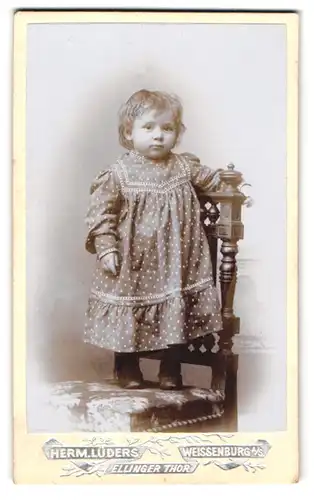 Fotografie Herm. Lüders, Weissenburg, Ellinger Thor, Kleines Mädchen im gepunkteten Kleid auf einem Stuhl