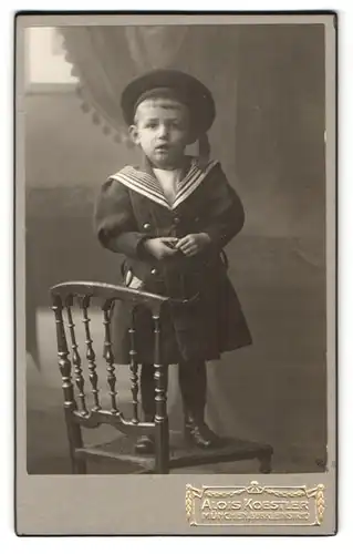 Fotografie Alois Koestler, München, Bürkleinstr. 10, Junger Knabe in Matrosenhemd und -mütze und einem Mantel