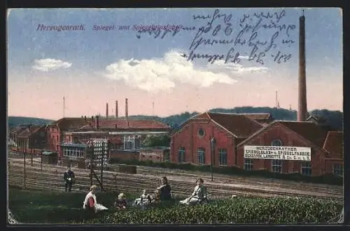 AK Herzogenrath, Spiegel- und Spiegelglasfabrik mit Bahnschienen und Gruppe im Gras, Briefträger