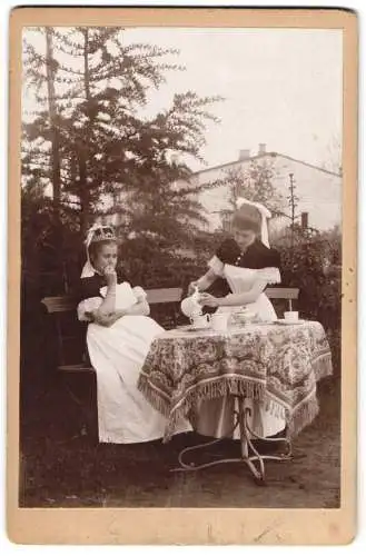 Fotografie unbekannter Fotograf und Ort, zwei Dienstmädchen / Hausmädchen beim Kaffeklatsch im Garten