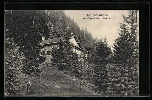 AK Brünnsteinhaus, Blick den Waldhang hinauf zur Berghütte bei Oberaudorf, mit Hüttenstempel