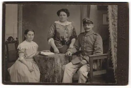 Fotografie Hugo Schwerg, Pirna, Albertstr. 13, Soldat Rgt. 12 in Uniform mit Schnauzbart neben Ehefrau u. Tochter