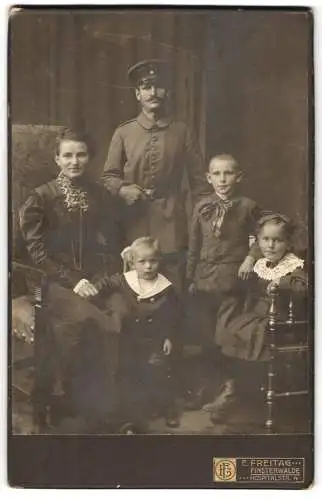 Fotografie E. Freitag, Finsterwalde, Hospitalstr. 4, Soldat in Feldgrau-Uniform u. Schirmmütze mit Ehefrau u. Kindern