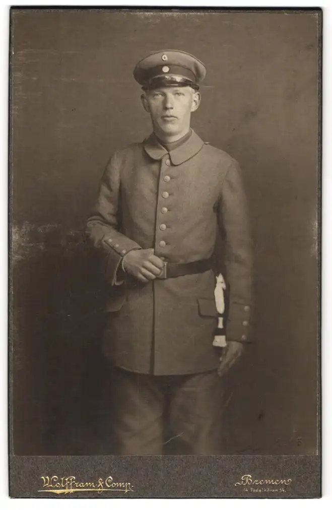 Fotografie Wolffram, Bremen, Fedelhören 14, Soldat in Feldgrau-Uniform mit Schirmmütze u. Bajonett