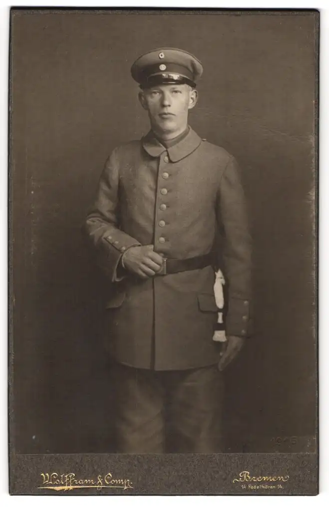 Fotografie Wolffram, Bremen, Fedelhören 14, Soldat in Uniform Feldgrau m. Schirmmütze u. Bajonett