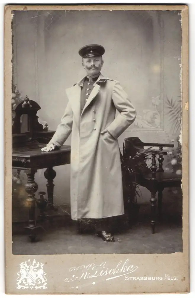 Fotografie J. K. Lischka, Strassburg i. E., Schreiberstubgasse 6, Offizier in Uniform u. Mantel m. Schirmmütze