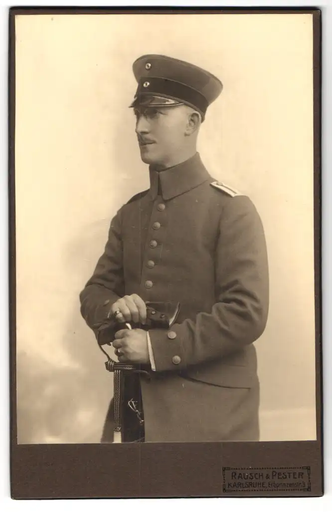 Fotografie Rausch & Pester, Karlsruhe, Erbprinzenstr. 3, Soldat in Uniform m. Schirmmütze u. Säbel
