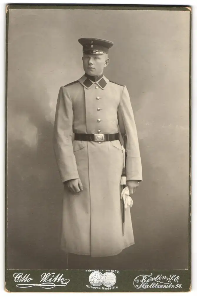 Fotografie Otto Witte, Berlin, Skalitzerstr. 54, Soldat in Uniform u. Mantel m. Schirmmütze u. Bajonett