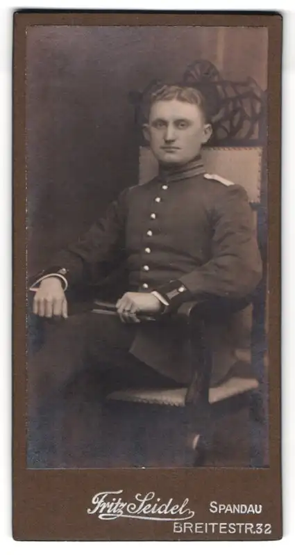 Fotografie Fritz Seidel, Spandau, Breitestr. 32, Soldat in Uniform mit Mittelscheitel sitzt auf Lehnstuhl