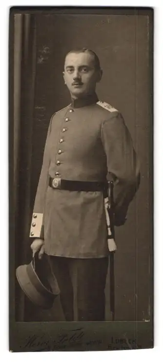 Fotografie Herm. Feldt, Lübeck, Breitestr. 31, Soldat in Uniform des Regiments 162 mit Degen hält Schirmmütze