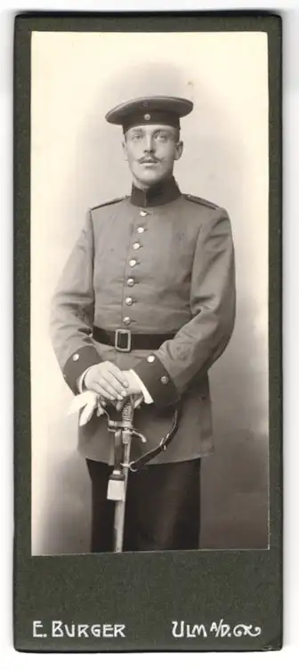 Fotografie E. Burger, Ulm a. d. D., Soldat in Uniform mit Schirmmütze und Degen