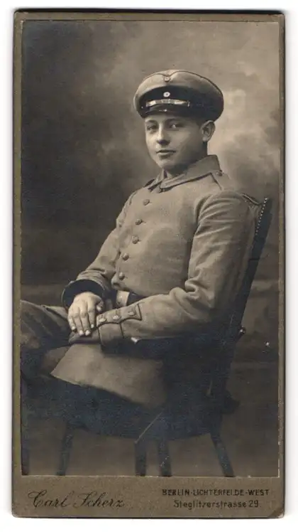 Fotografie Carl Scherz, Berlin-Lichterfelde-West, Steglitzerstr. 29, Soldat in Uniform mit Schirmmütze lässig im Stuhl