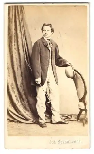 Fotografie Joh. Spannbauer, Wien, junger Mann im hellen Anzug mit Sacko und Melone, Flanierstock