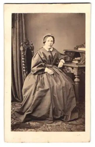 Fotografie Berthold Woltze, Halberstadt, ältere Dame im Kleid posiert sitzend am Sekretär