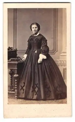 Fotografie L. Steinmann, Braunschweig, junge Dame im dunklen Kleid stehend am Sekretär