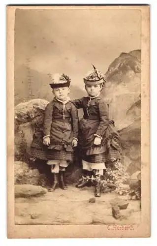 Fotografie C. Herberth, Wien, zwei niedlichen Kinder in Kleidern mit Hüten vor einer Studiokulisse