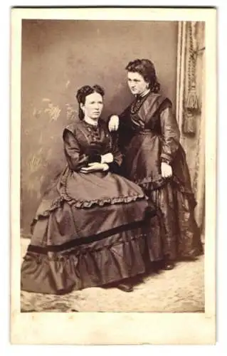 Fotografie unbekannter Fotograf und Ort, zwei junge Frauen in dunklen Kleidern mit Perlenkette