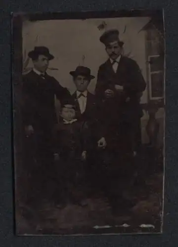 Fotografie Ferrotypie drei Herren mit jungem Knaben vor einer Studiokulisse
