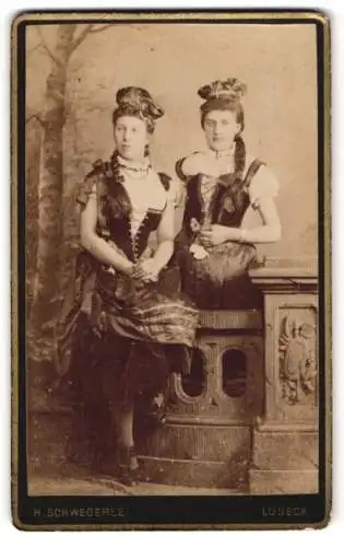 Fotografie H. Schwegerle, Lübeck, zwei junge Frauen in Trachtenkleidern zum Fasching mit geflochtenem Zopf