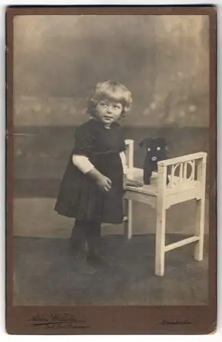 Fotografie Atelier Wilhelm, Neunkirchen, Blondes kleines Mädchen im Kleid mit Stoffhund, Spielzeug, Knopfaugen