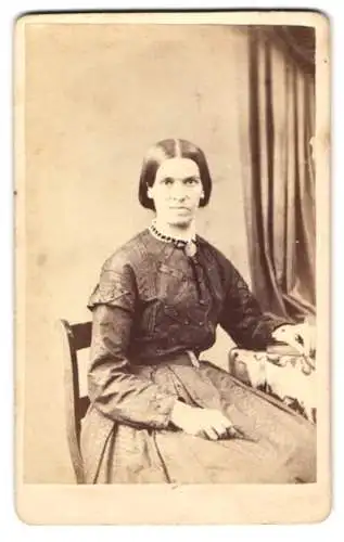 Fotografie C. Grote, Arnsberg, Königstr. 330, junge Frau im Kleid mit Brosche, sitzend am Tisch