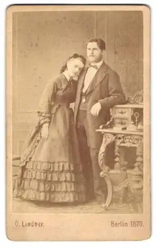 Fotografie O. Lindner, Berlin, junges Paar im Anzug und im Kleid lehnent am Sekretär