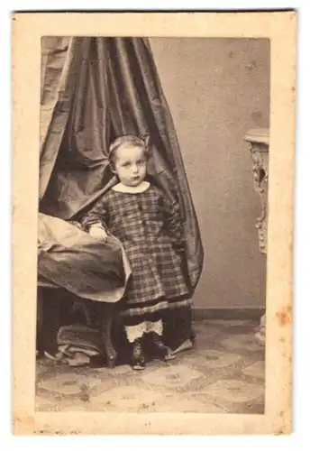 Fotografie Bodo Winsel, München, niedlicher kleiner Knabe im karierten Kleid vor einem Vorhang