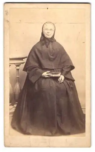 Fotografie unbekannter Fotograf und Ort, Dame im schwarzen Kleid mit Überwurf und Haube, Kruzifix in der Hand
