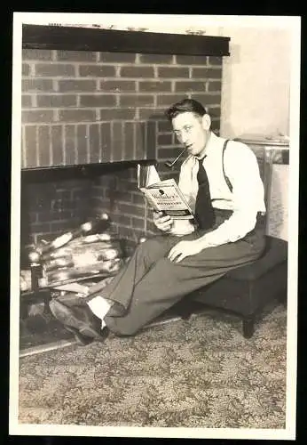 Fotografie USA 1939, Gentleman mit Pfeife liest Webster's Dictionary vor dem offenen Kamin