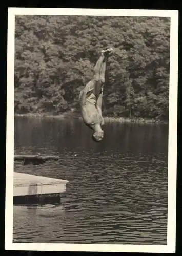 Fotografie Kunstspringer steht beim Salto kopfüber ober der Wasseroberfläche