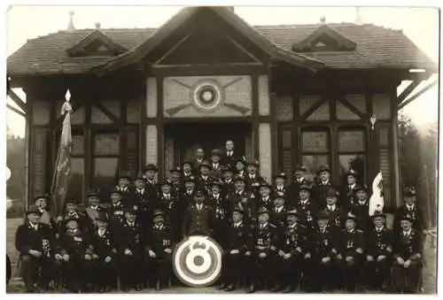 Fotografie Schützengilde Gruppenbild vor Schützenhaus mit Zielscheibe & Standartenträger