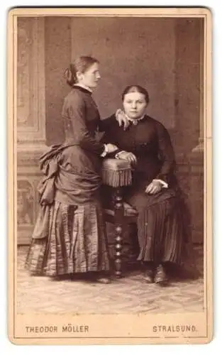 Fotografie Theodor Möller, Stralsund, Mutter und Tochter in Kleidern posieren im Atelier