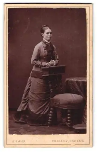 Fotografie J. Laux, Koblenz, junge Frau im Gründerzeitkleid posiert an einem Stuhl