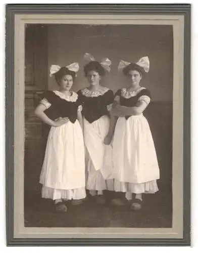 Fotografie unbekannter Fotograf und Ort, drei junge Niederländerinnen in Tracht mit Holzschuhen / Clog