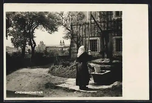 AK Kremsmünster, Alte Frau am Brunnen mit Blick auf Stift und Sternwarte