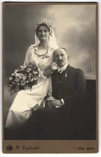 Fotografie Fr. Engelmaier, Nem. Brod, Komenskehi 17, Brautpaar Anny & Vojecka im Brautkleid und Anzug, 1919