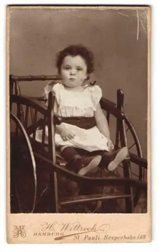 Fotografie H. Wittrock, Hamburg-St. Pauli, junges Mädchen im Kleidchen sitzt im Kinderwagen