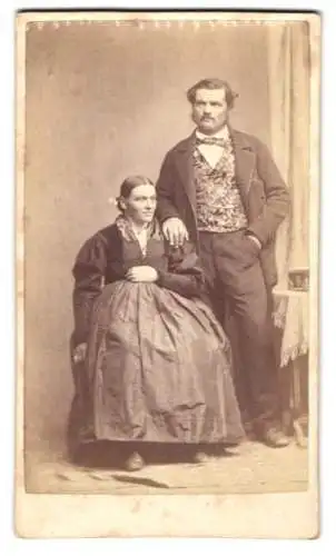 Fotografie unbekannter Fotograf und Ort, Mann und Frau im Kleid und im Anzug mit gemusterter Weste