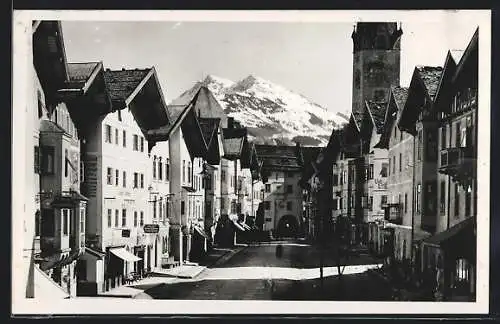 AK Kitzbühel, Partie mit Geschäften und Gebirge im Hintergrund