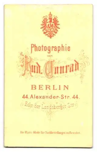 Fotografie Rud. Conrad, Berlin, Alexander-Str. 44, Bürgerliche Dame in mehrlagigem Kleid mit weisser Kopfbedeckung